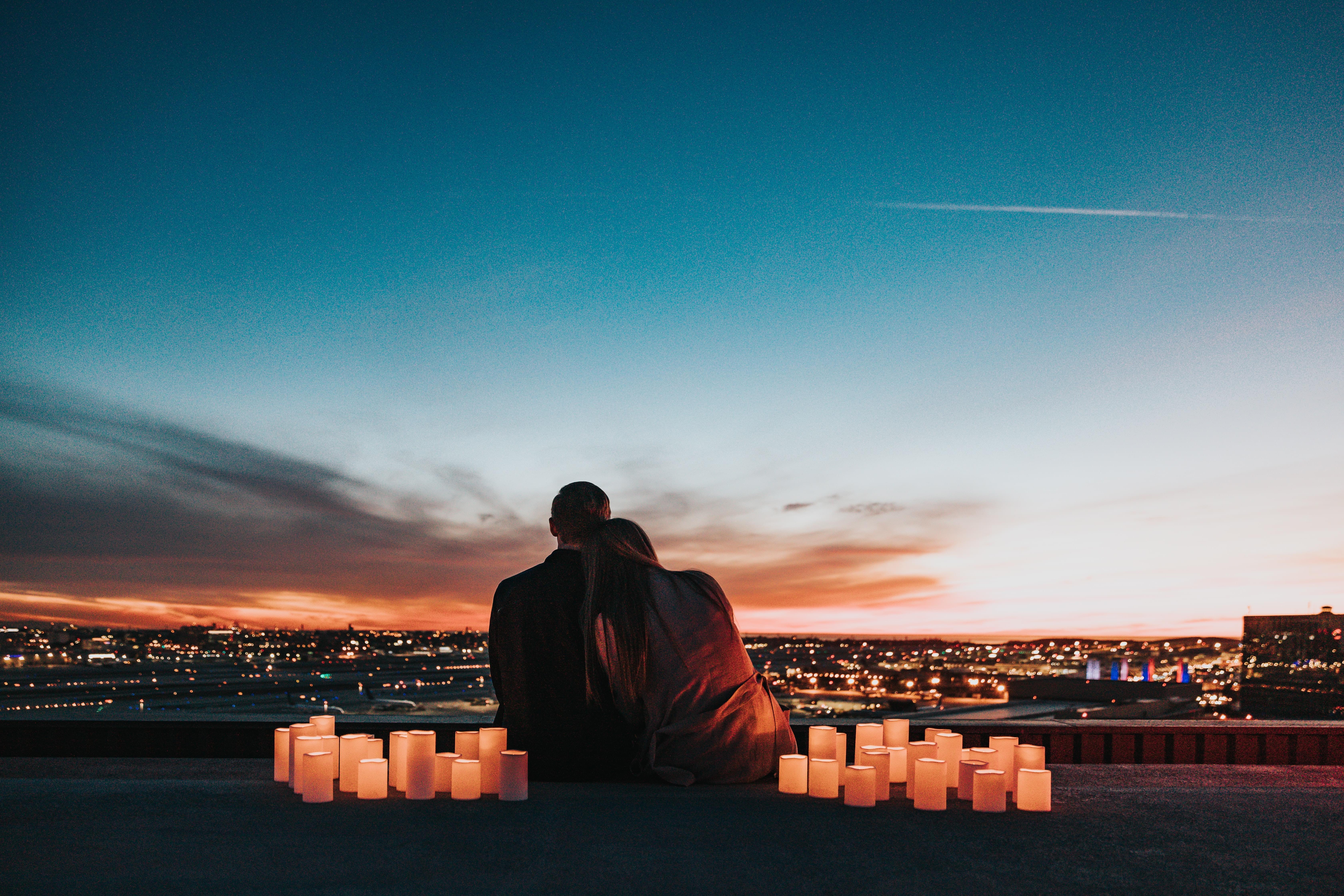 A couple embracing in front of a city skyline at sunset, representing real human connection.